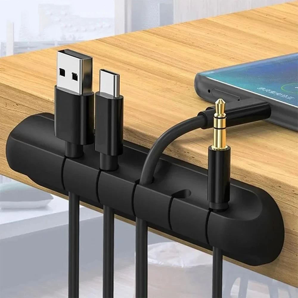 Black silicone desk cable organizer clip bar with raised slots holding charging cables