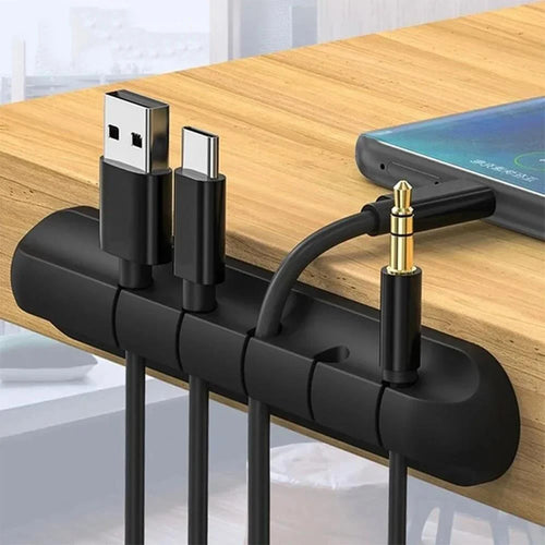 Black silicone desk cable organizer clip bar with raised slots holding charging cables